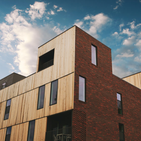 Exterior of a three story building with cypress siding and rooftop deck