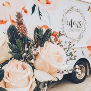 A bouquet of roses and a baby pineapple in front of Eden's colorful flower truck