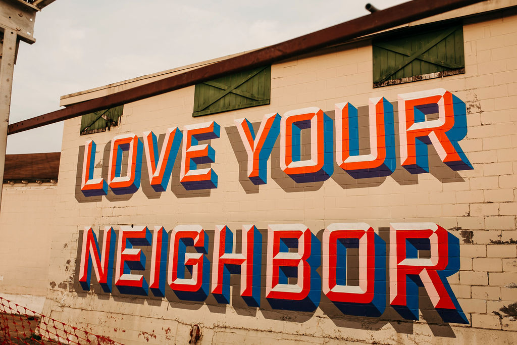 Bold mural on an old industrial building with the words LOVE YOUR NEIGHBOR