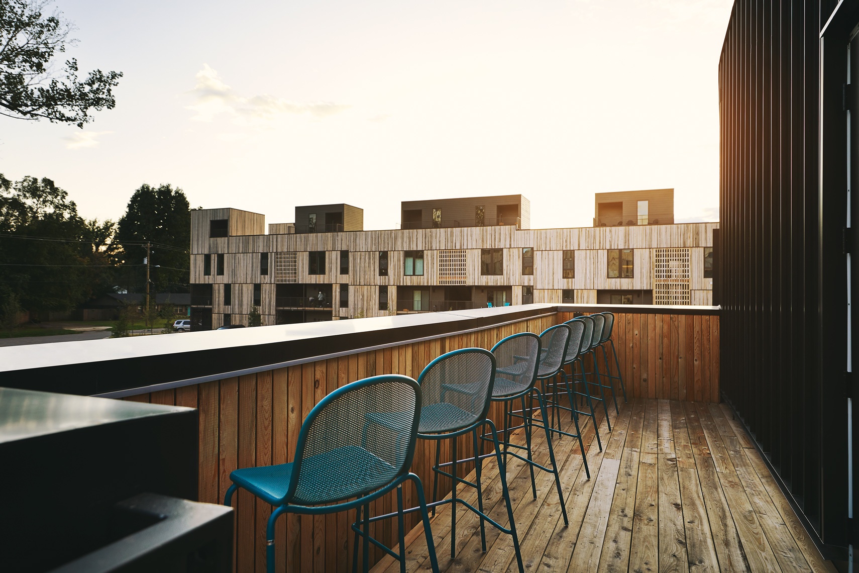 Tall stools line a counter at the edge of a balcony overlooking a courtyard