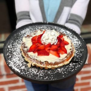 Strawberry cheesecake waffles sprinkled with powdered sugar
